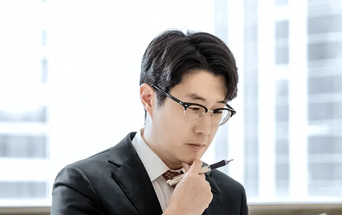 펜을 들고 생각에 잠긴 박진우 대표변호사